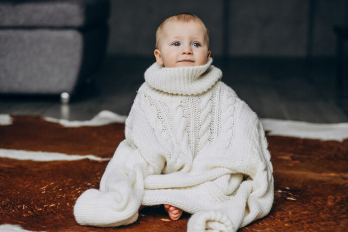 Bebê com frio sentado no chão com blusa de manga longa